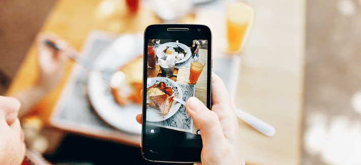 Carbos, a carbs counting app on a smartphone with healthy, balanced meal in the background. Image illustrates the benefits of using carb counting apps for diabetes management.